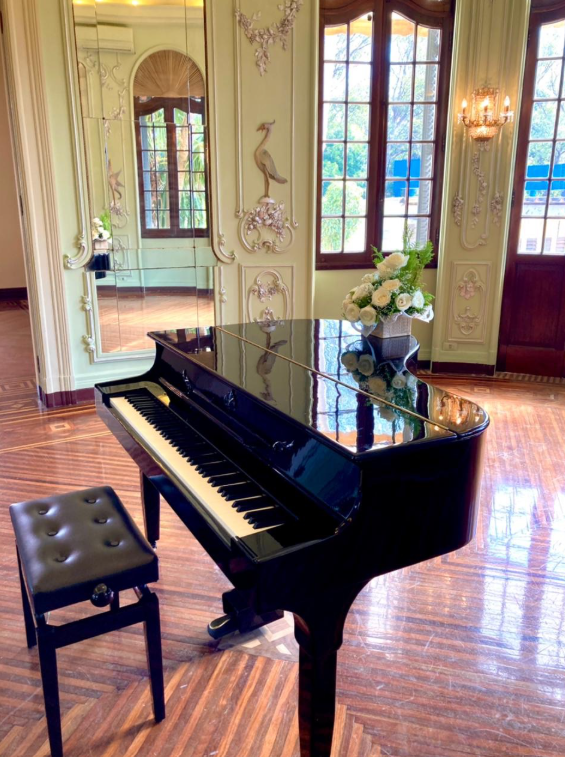 Piano preto e banco em um salão de arquitetura clássica iluminado por janelas