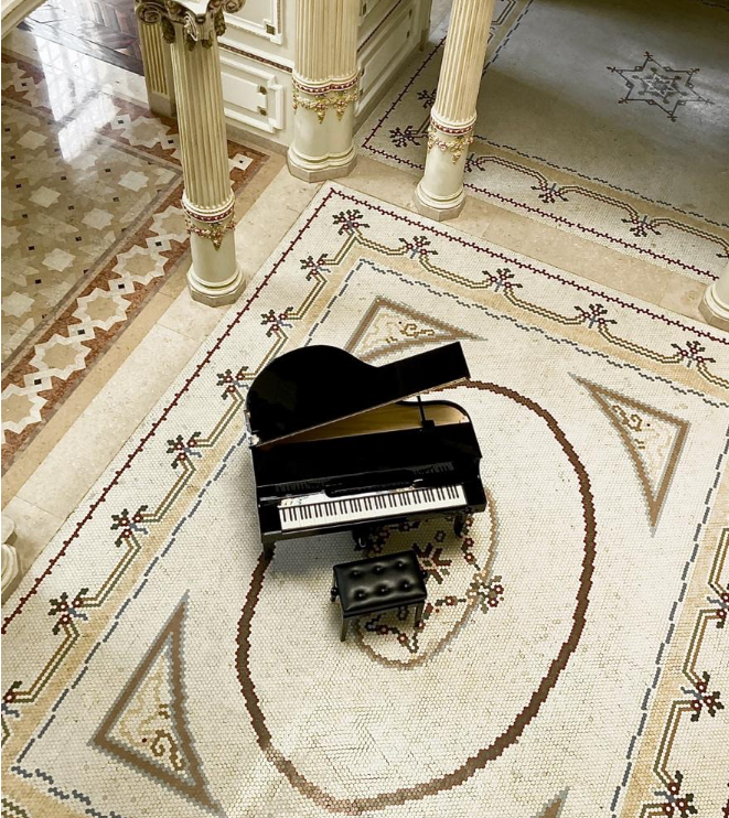 Piano preto visto do alto, entre colunas e o desenho de um piso clássico