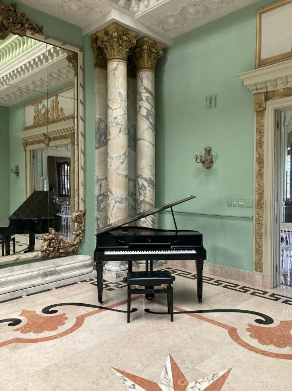 Piano preto diante de espelhos e colunas de mármore em um salão